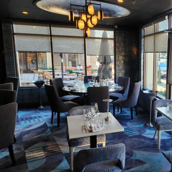 Elegant dining room at Jessica's Restaurant with set tables, modern chandelier, and large windows.
