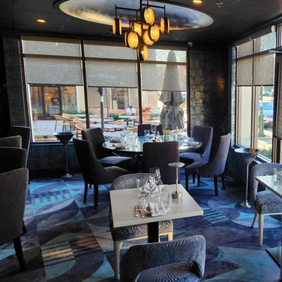 Elegant dining room at Jessica's Restaurant with set tables, modern chandelier, and large windows.