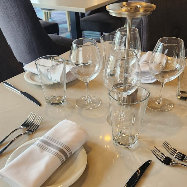 A set table at Jessica's Restaurant with wine glasses, water glasses, and folded napkins.