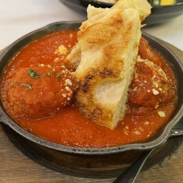 Meatballs in red sauce with parmesan and basil, served in a skillet with toasted bread.