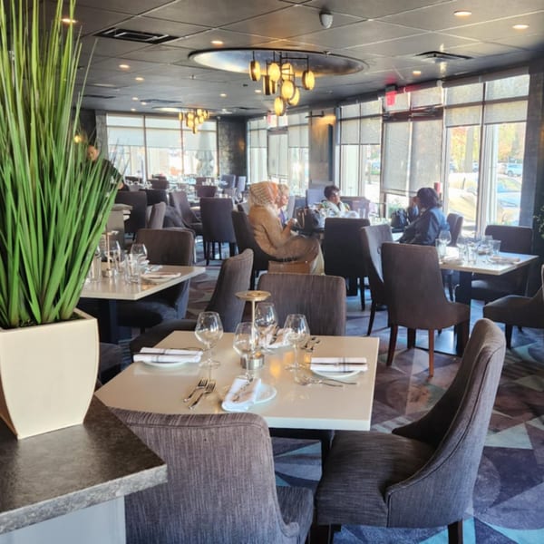 Jessica's Restaurant dining room with set tables, plush chairs, and large windows overlooking a street.