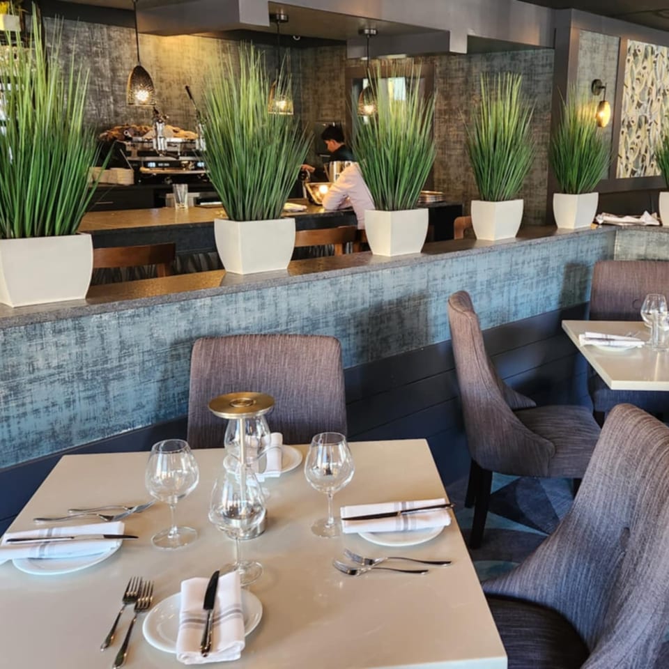 Jessica's Restaurant dining room with set tables, modern chairs, and a bar area with a barista.
